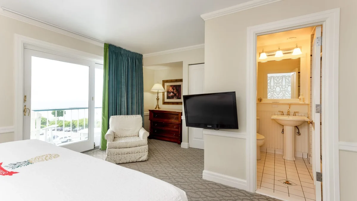 A hotel bedroom with bathroom, chair, and bed.