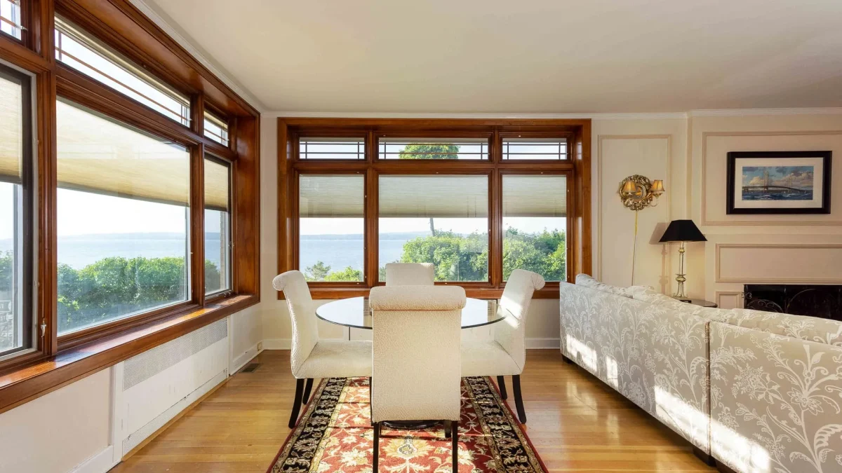 A living room with a table and open windows.