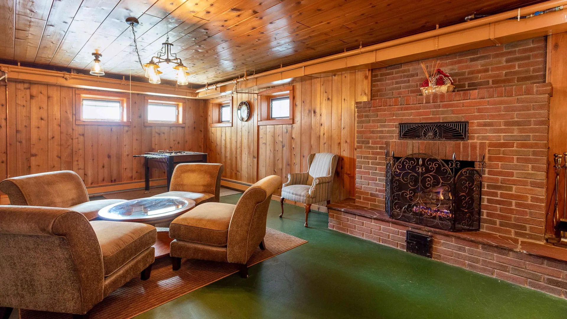 A man cave with wood paneling and four chair seating.