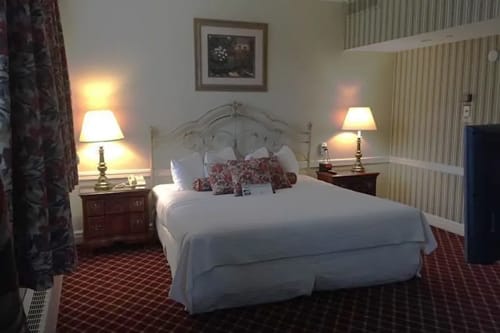 Hotel bedroom with king bed, matching lamps and framed floral artwork.