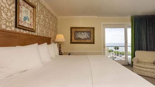 Hotel king bed with framed artwork and balcony doors overlooking the water.